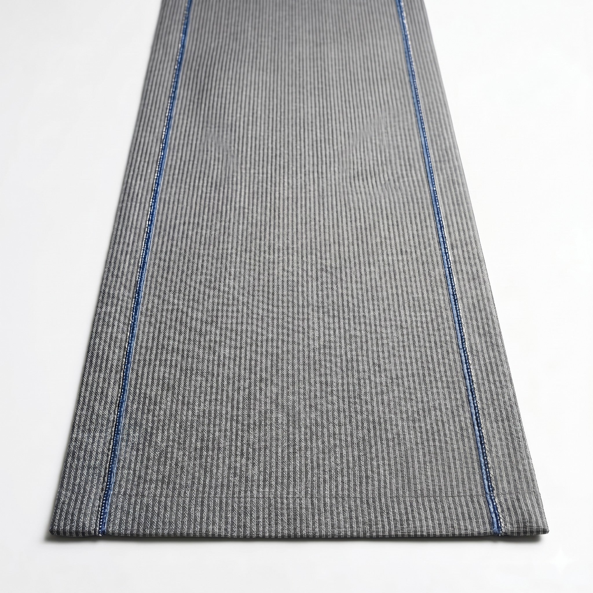 Gray textured rug with blue stitching on a white background