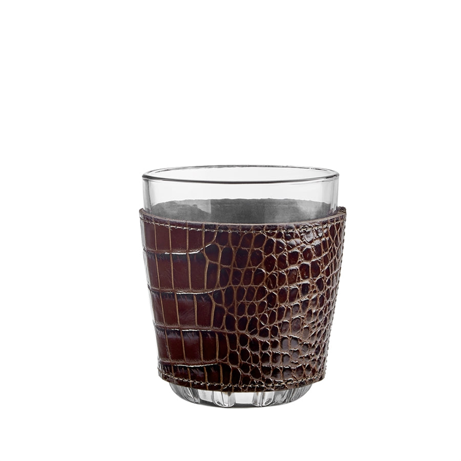 Clear glass with a brown crocodile-patterned leather sleeve on a white background