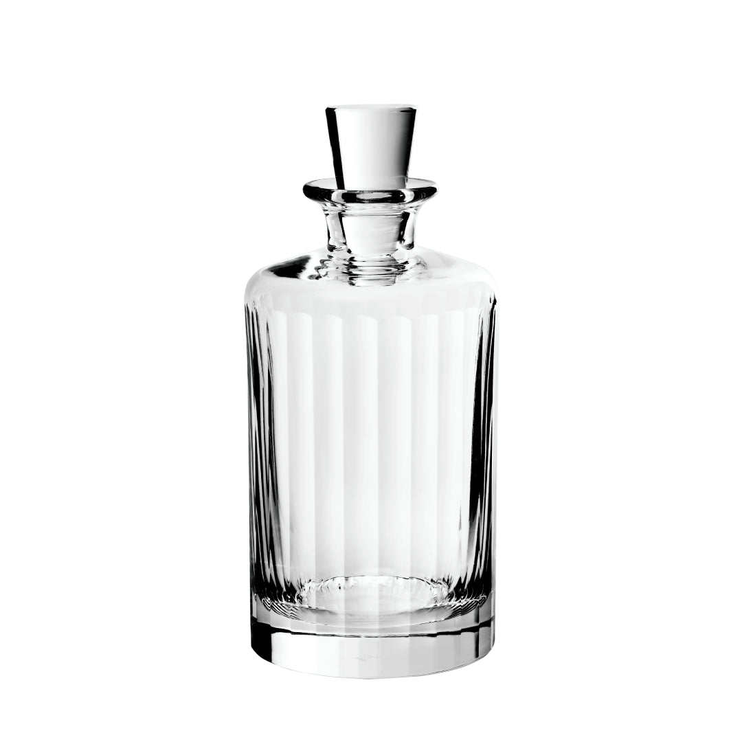 A clear glass large decanter with a fluted design and a stopper on white background