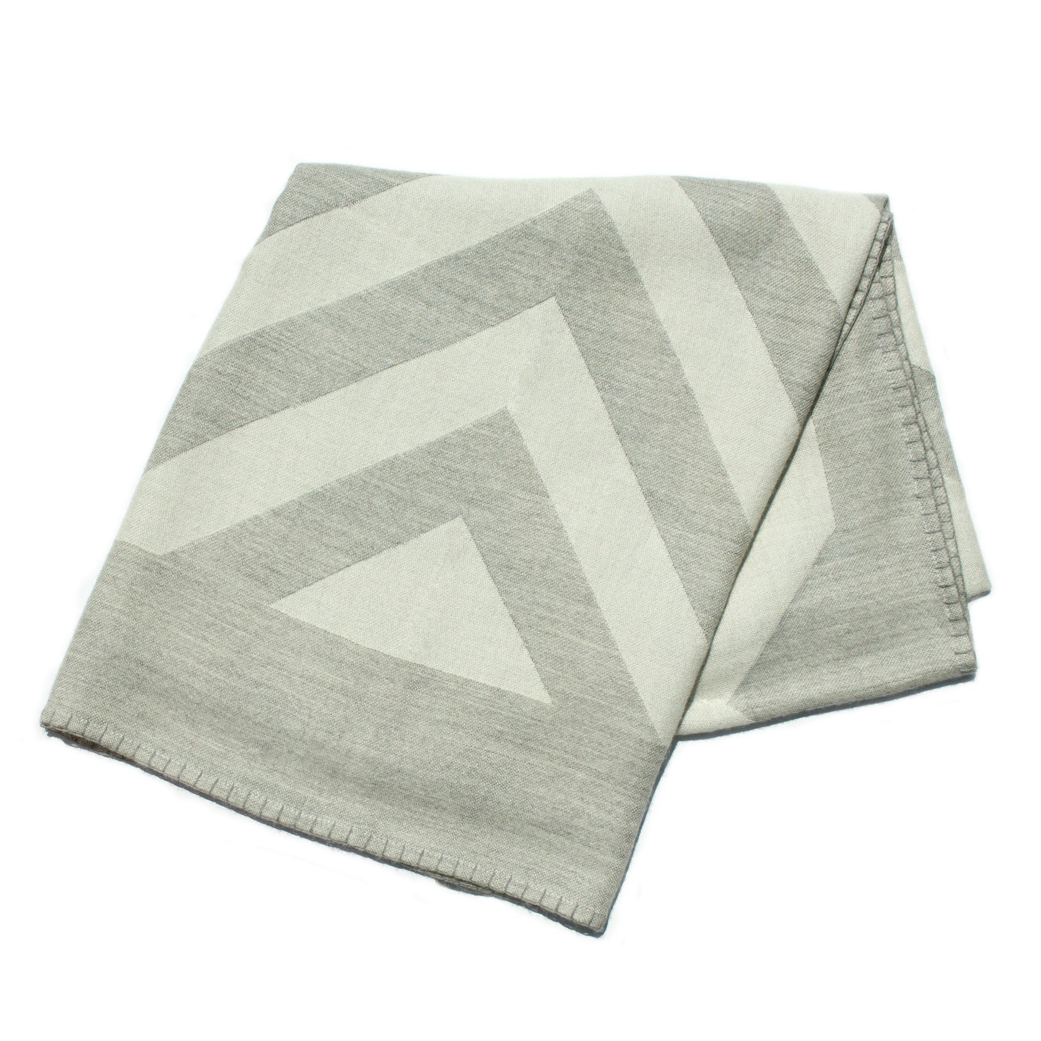 Folded gray and white geometric patterned blanket on a white background