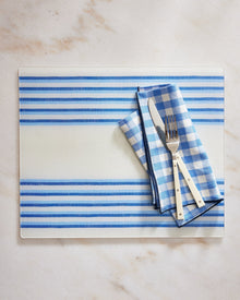 Blue and white striped placemat with cutlery on a marble surface