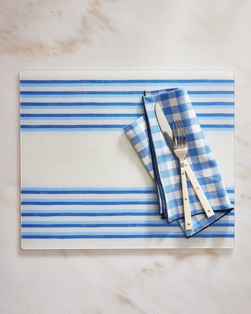 Blue and white striped placemat with cutlery on a marble surface