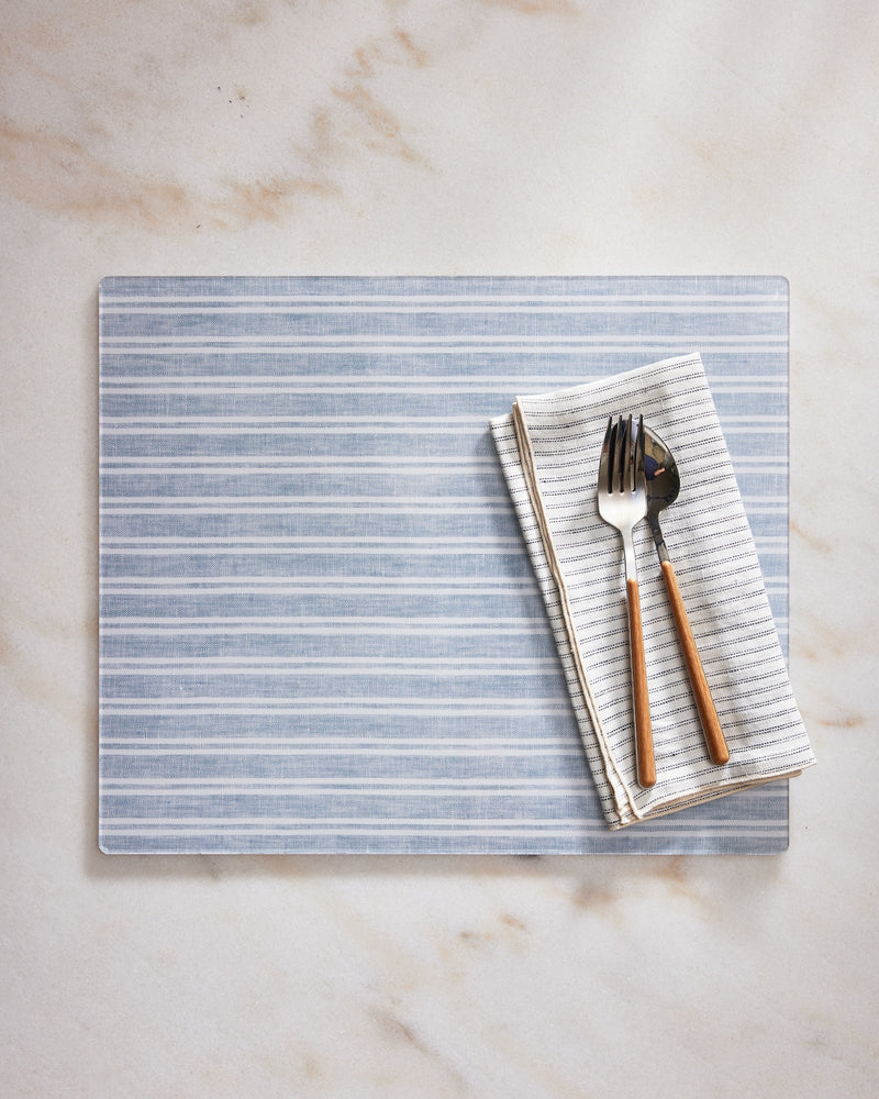Striped placemat with folded napkin and cutlery on a marble surface