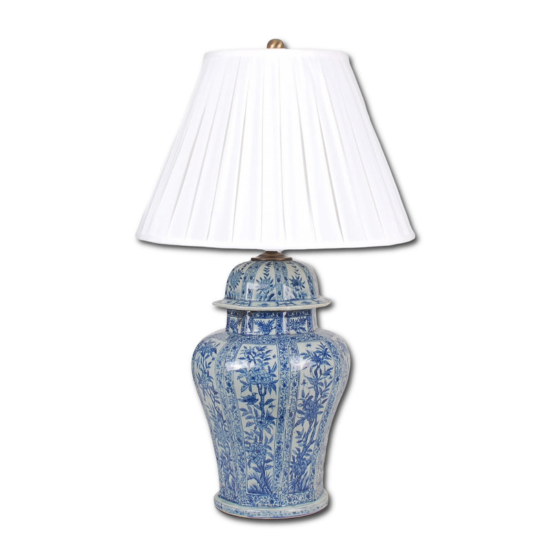 Blue and white ceramic lamp with a pleated white shade on a white background