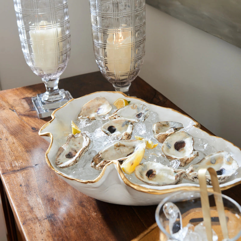 Oysters on a half shell in a decorative dish with lemon wedges, served on a wooden table.
