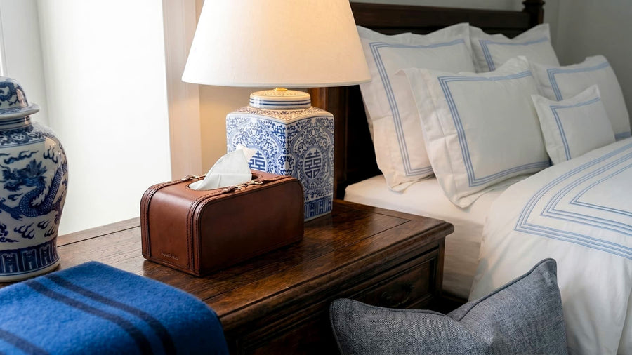 Bedroom scene with a wooden nightstand, lamp, and decorative items.