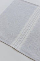 Close-up of a light gray linen placemat with subtle stripes on a white background