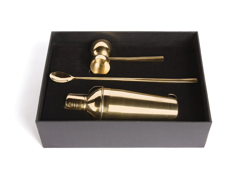 Gold cocktail shaker set with bar tools in a black box on a white background