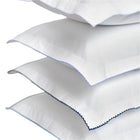 4 white fabric pillows with blue embroidery on a white background