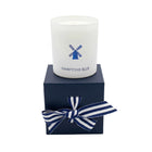 Candle in a white container with 'Hamptons Blue' branding on a navy box with a striped bow.