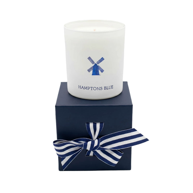 Candle in a white container with 'Hamptons Blue' branding on a navy box with a striped bow.