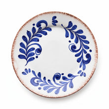 A round white ceramic plate with a rustic, hand-painted blue floral pattern and a textured, reddish-brown rim, shown from a top-down perspective on a white background.