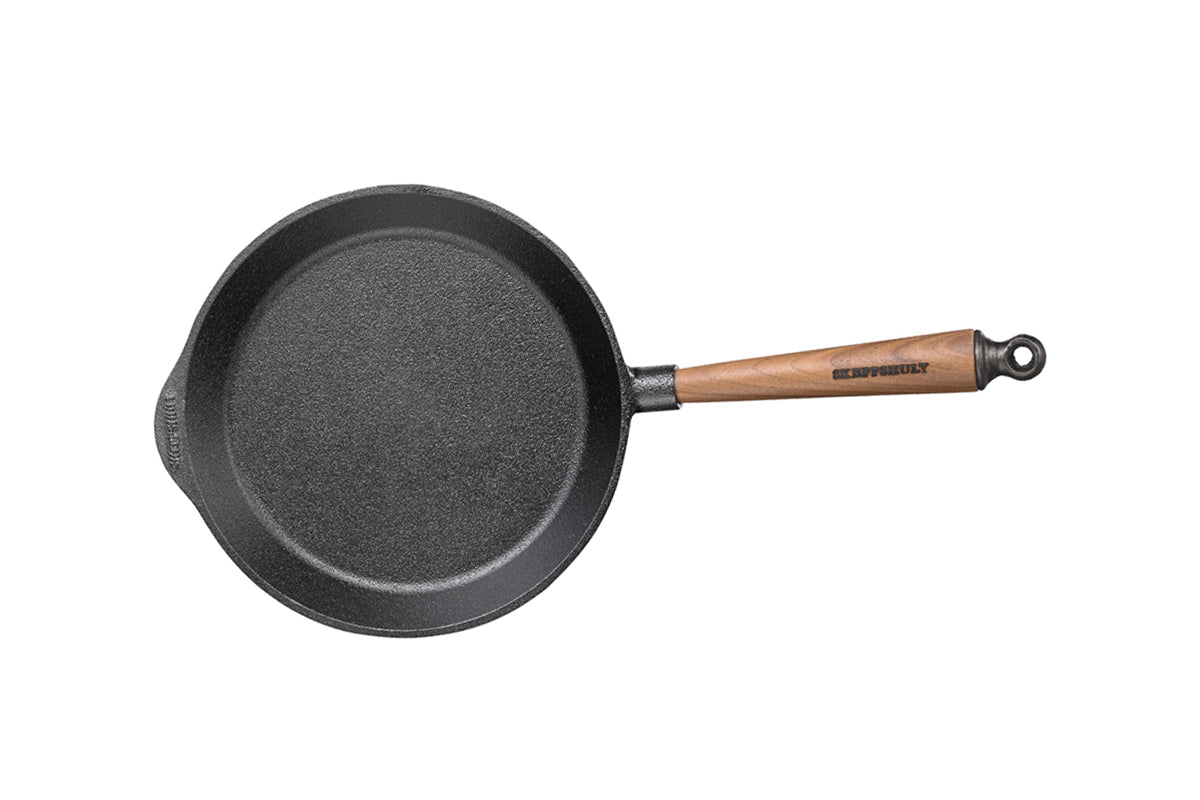 Black cast iron skillet with a wooden handle on a white background