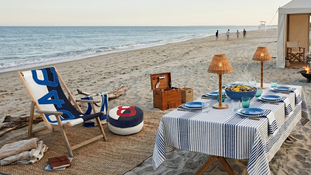 Beachside setup with table, chairs, and lanterns by the ocean