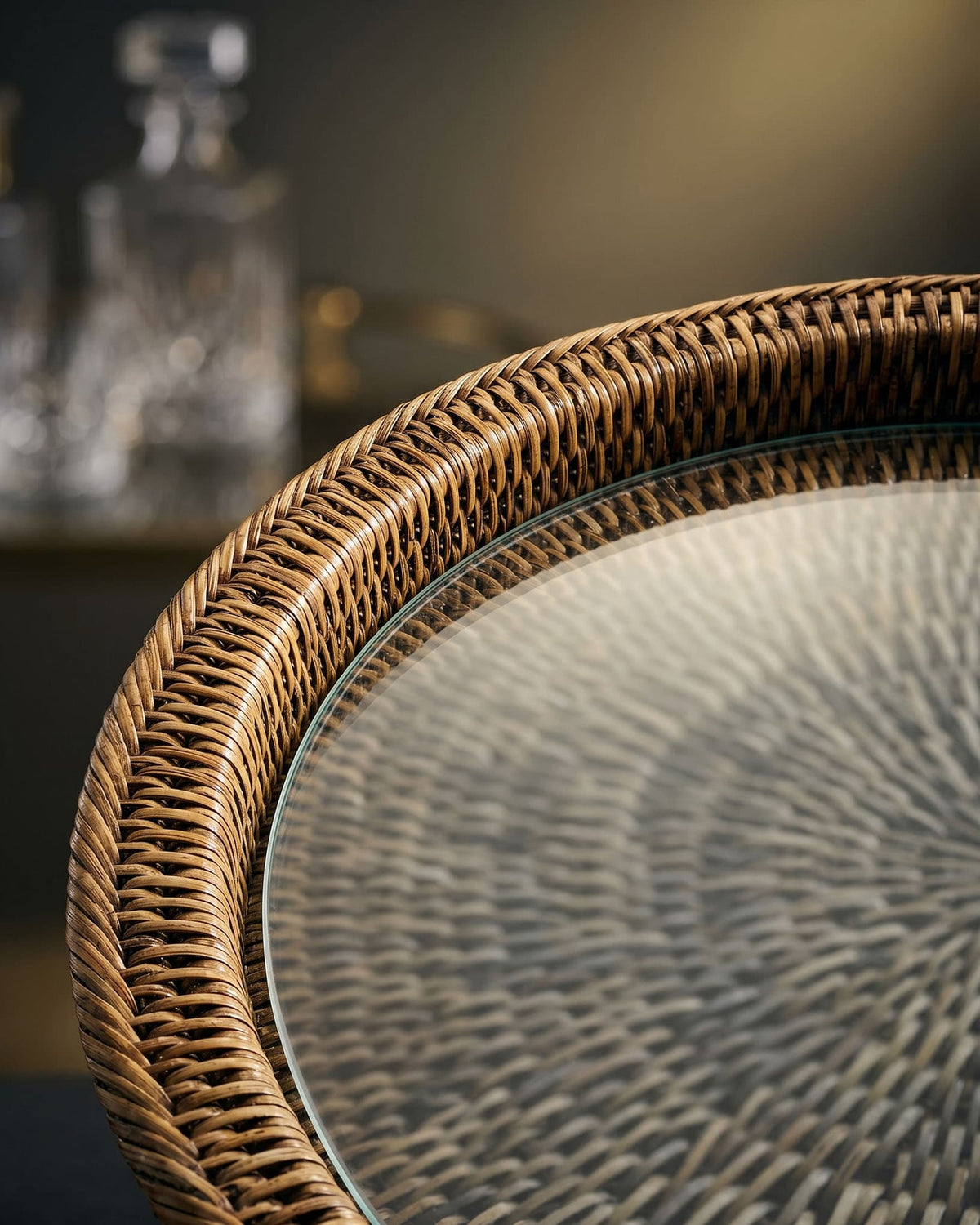 Round glass table with wicker edge on a blurred background