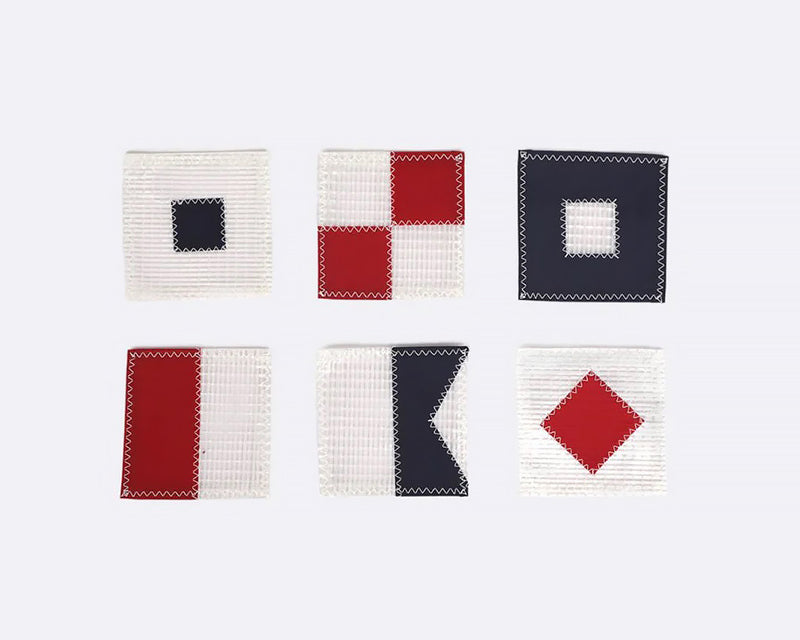 A set of six white square coasters with red and navy blue nautical flag designs, arranged in two rows of three.