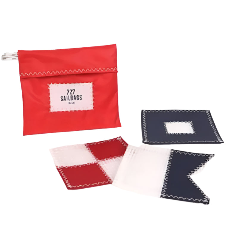 A red pouch with "727 SAILBAGS" on it and three nautical flag coasters (red/white, red/white checker, white/blue) scattered around it.