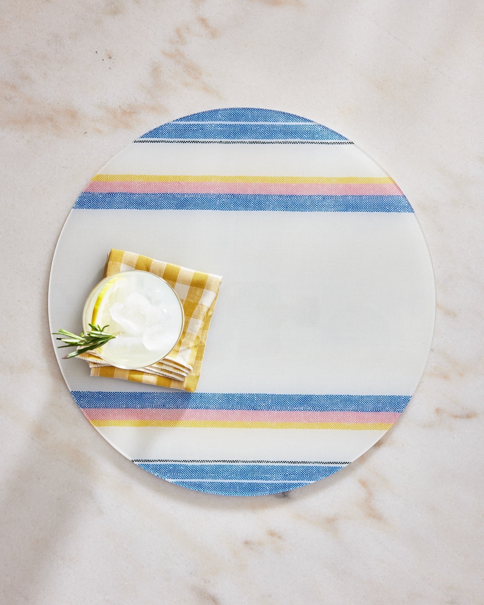 Round glass plate with blue and yellow striped rim on a marble surface