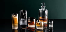 Whiskey decanter and glasses on a dark surface with a dark background