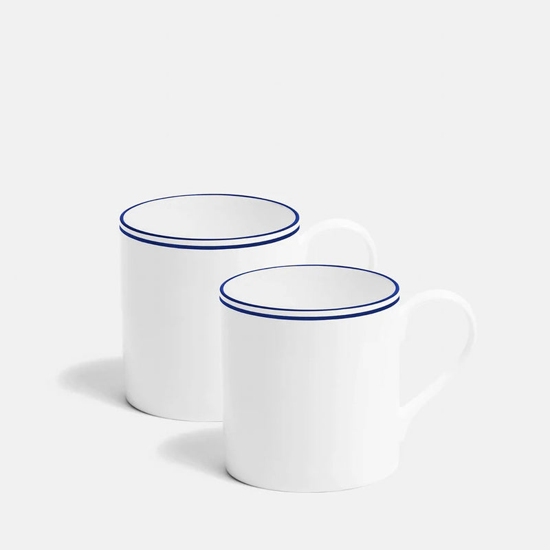 Two white mugs with blue rims on a light gray background
