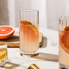 Clear fluted high ball glass filled with white and orange slice on marble table