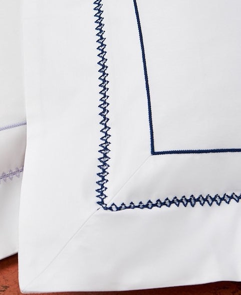Close up of white pillowcase with blue embroidery