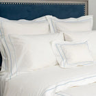 White pillows with blue stitching on a bed with a blue headboard.
