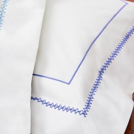 Close up of white pillowcase with blue embroidery