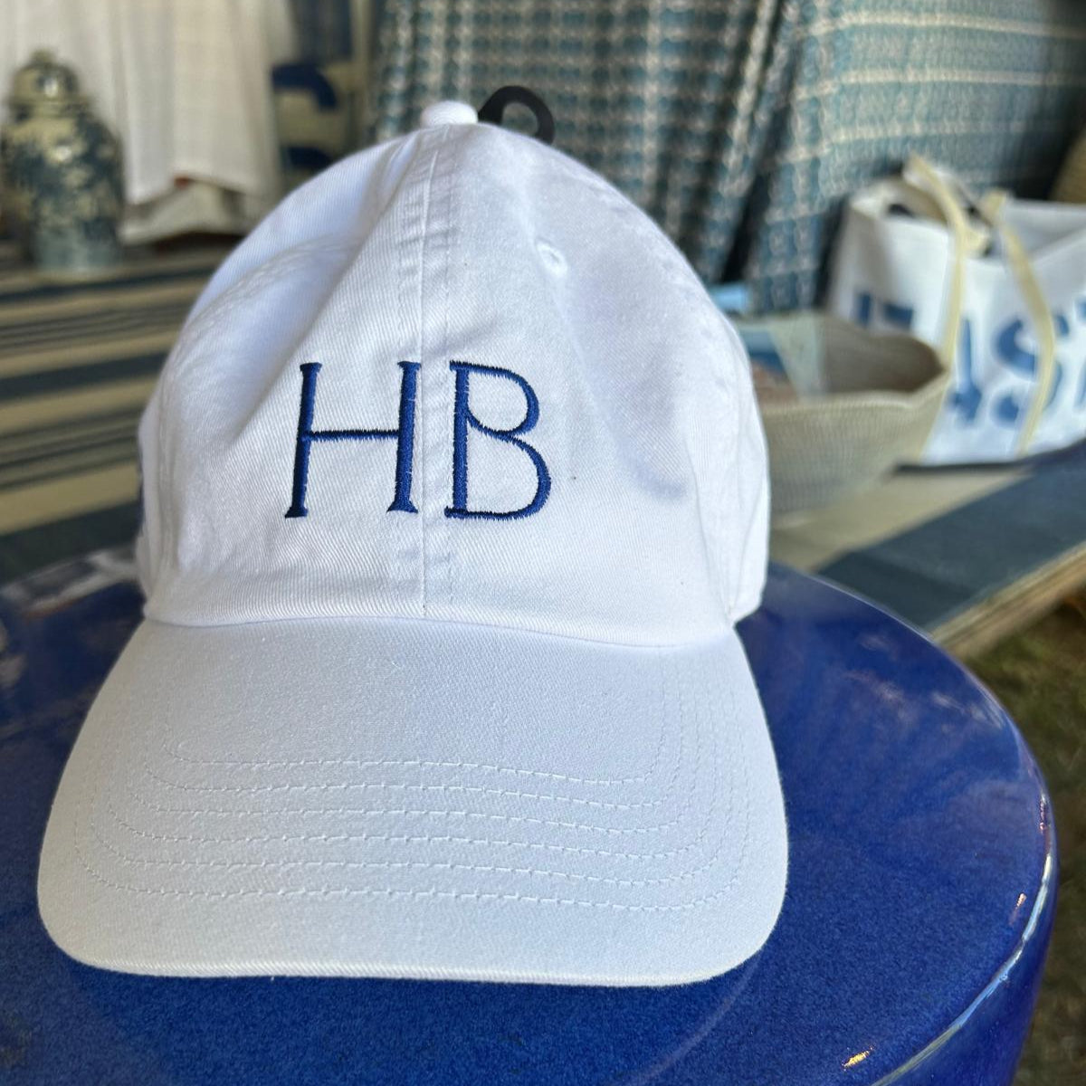 White cap with 'HB' embroidery on a blue surface