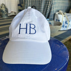 White cap with 'HB' embroidery on a blue surface
