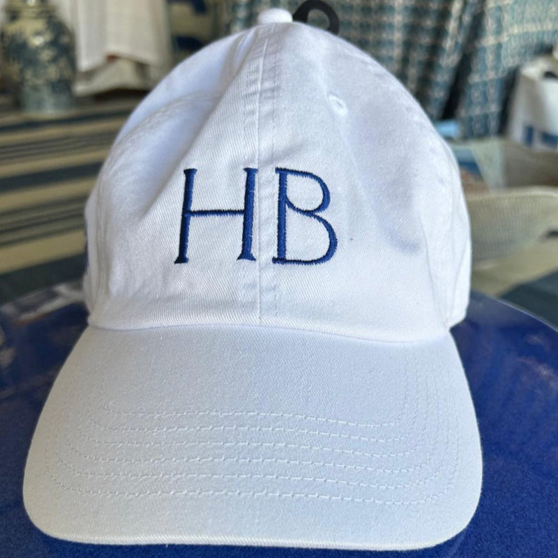 White cap with 'HB' embroidery on a blue surface
