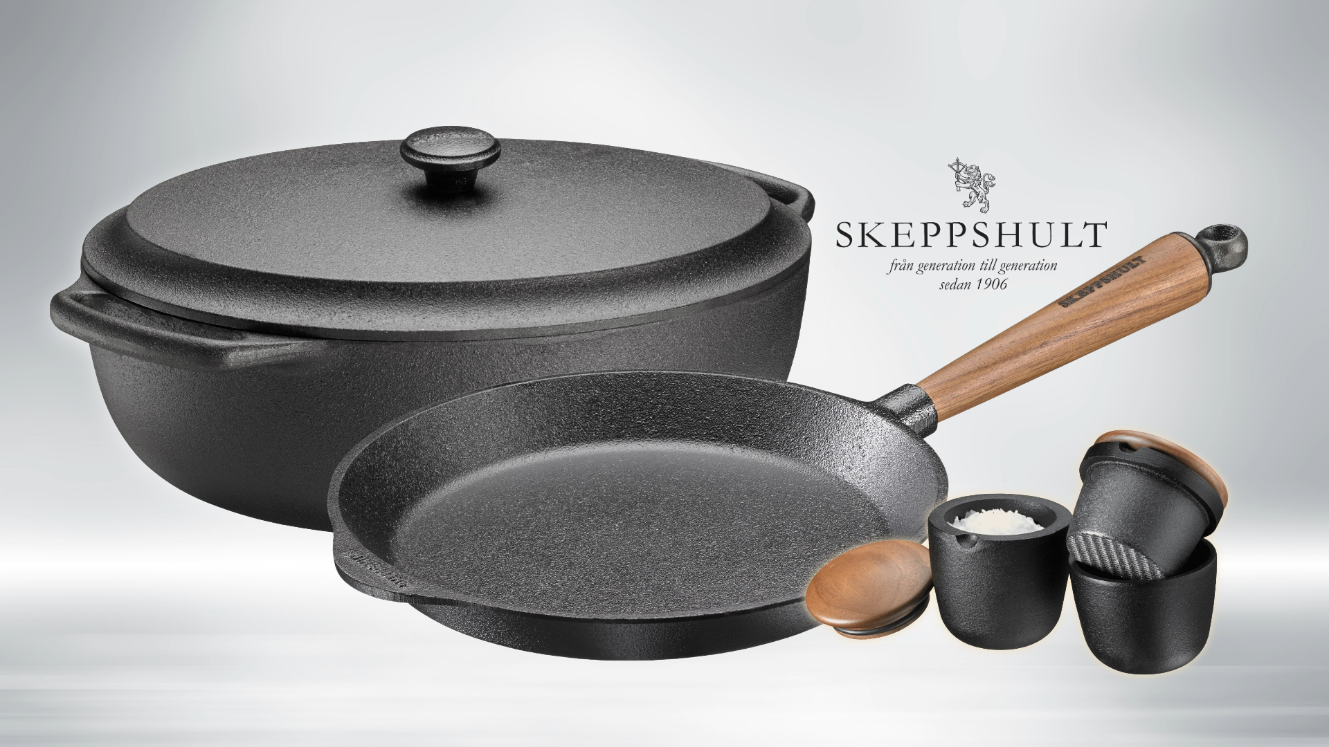 Set of black cast iron cookware with wooden handle on a light gray background, featuring the Skeppshult brand.