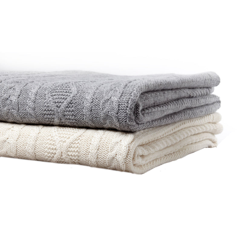 Folded gray & white cable knit blankets on a white background