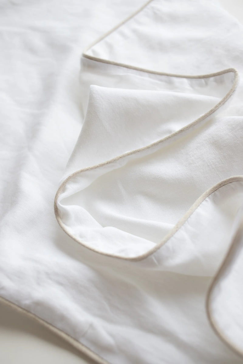 Close-up of a white sheet with a subtle pattern on a light background