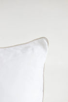 White pillow with a thin beige border on a white background