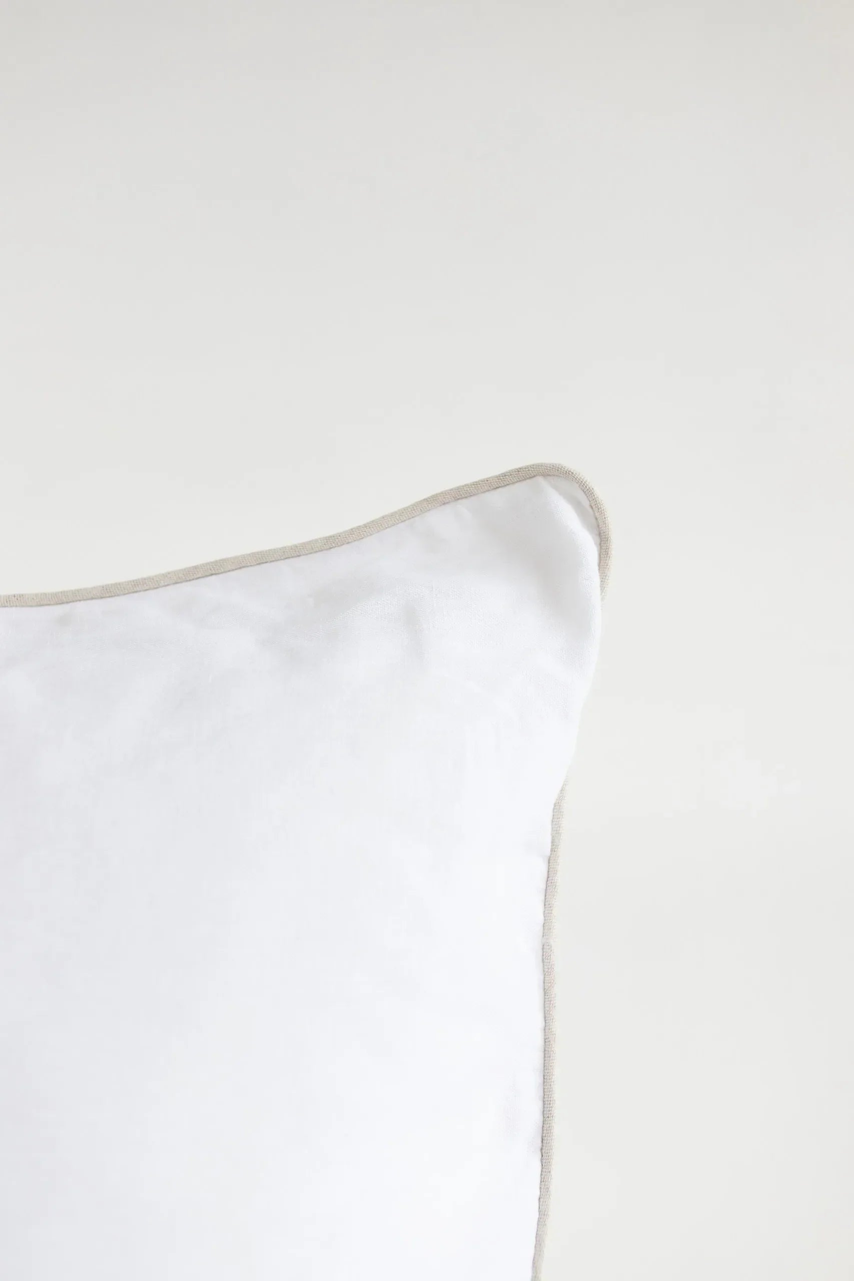 White pillow with a thin beige border on a white background