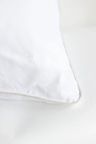 White pillow with a subtle beige trim on a white background
