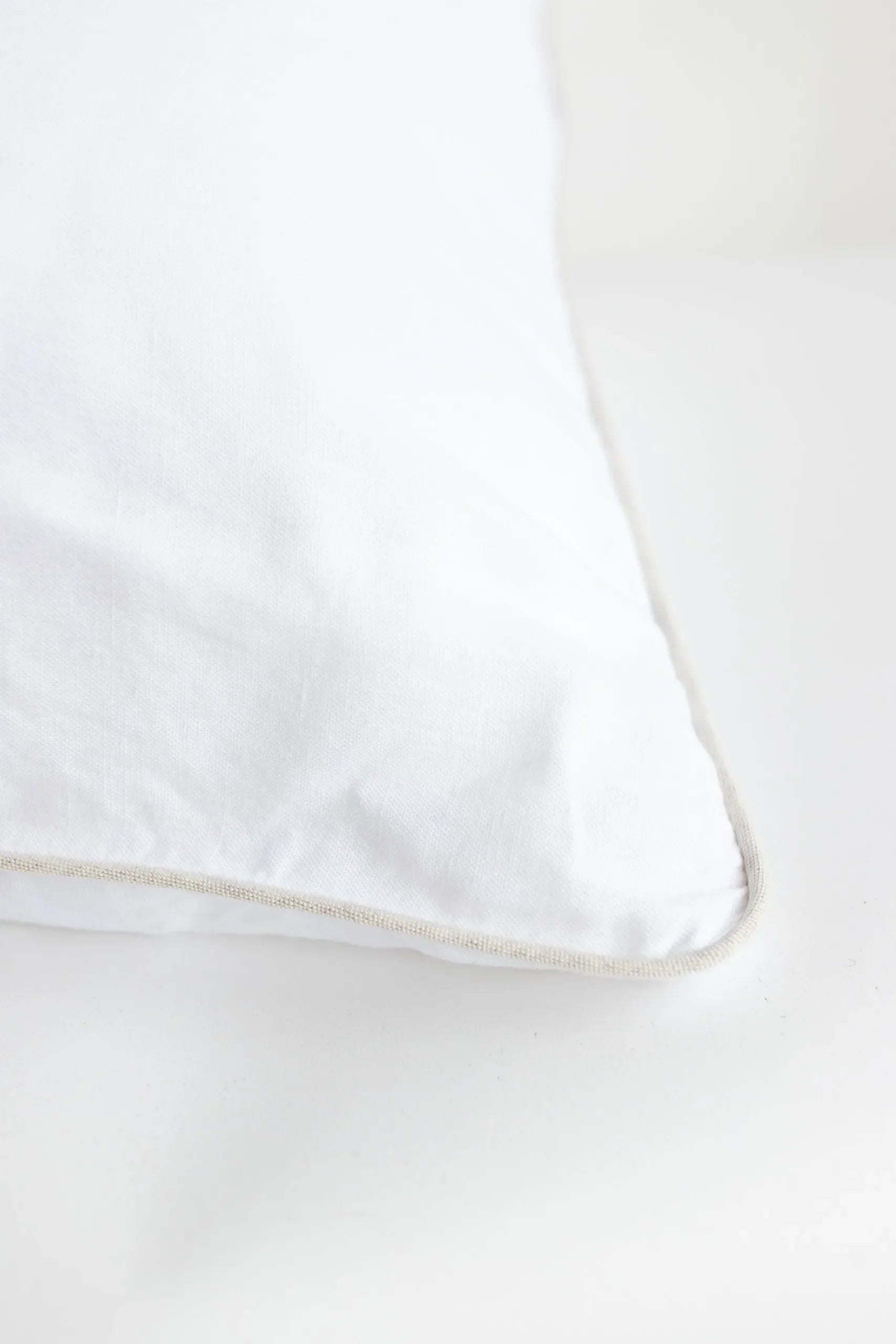 White pillow with a subtle beige trim on a white background