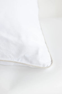 White pillow with a subtle beige trim on a white background