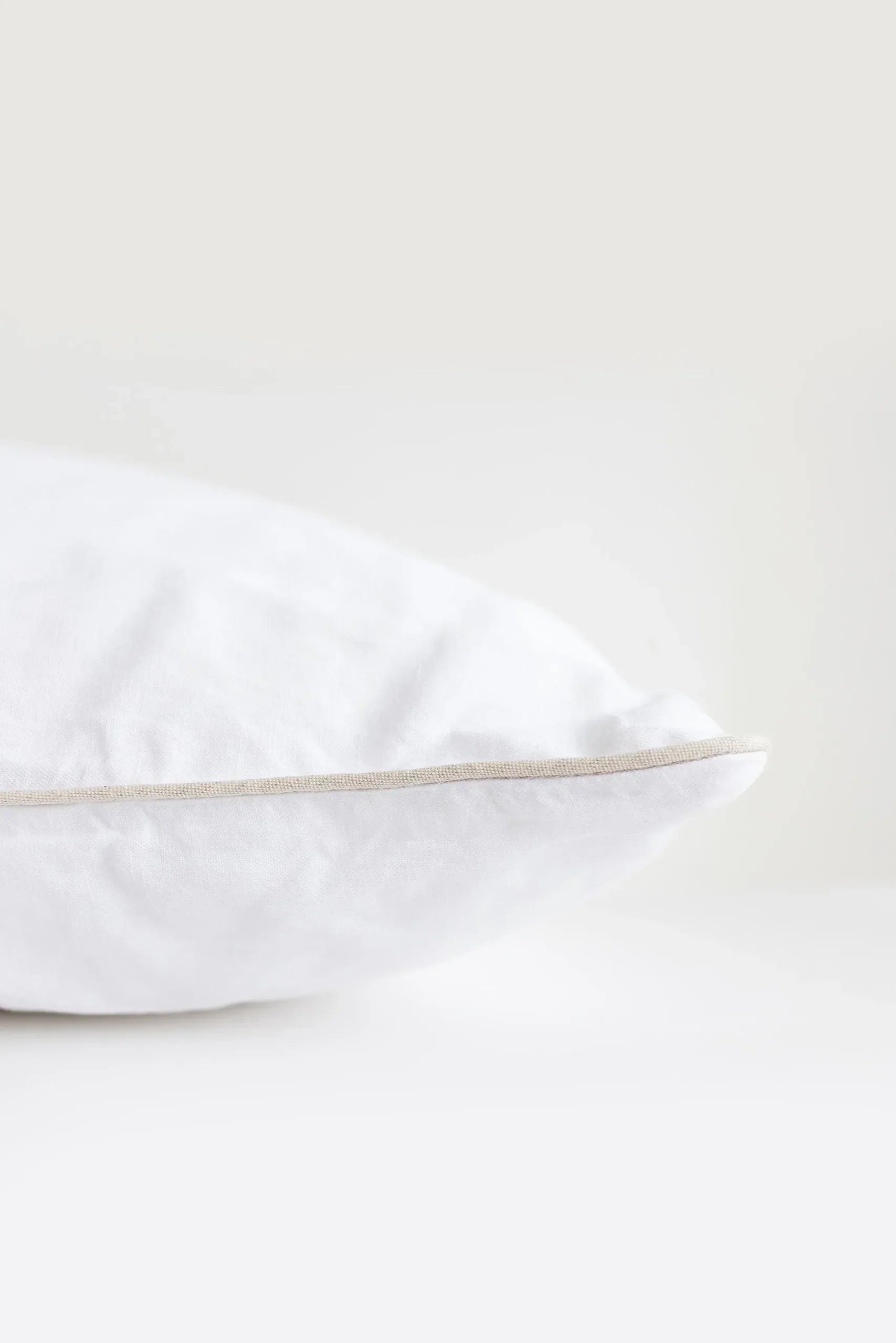 White pillow with a thin beige line on a white background