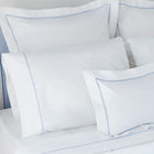 White pillows with blue piping on a bed