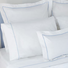 White pillows with blue piping on a bed
