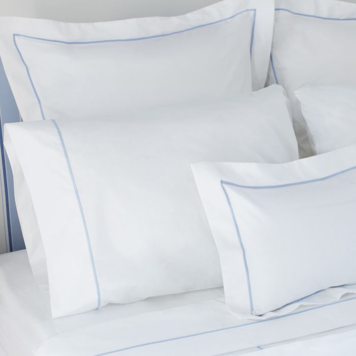 White pillows with blue piping on a bed