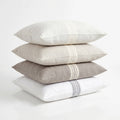 Stack of four pillows in white, beige, and gray on a light background