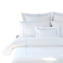 White bedding set with blue piping on a white background
