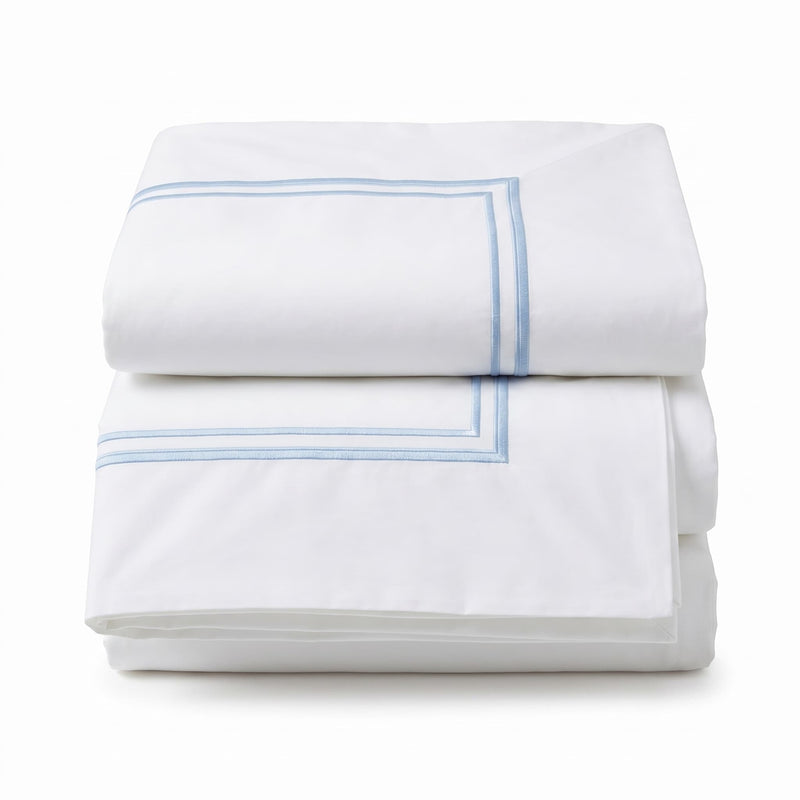 Folded white comforter with blue stitching on a light gray background