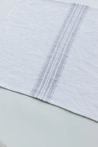 Close-up of a white placemat with gray stripes on a light green background