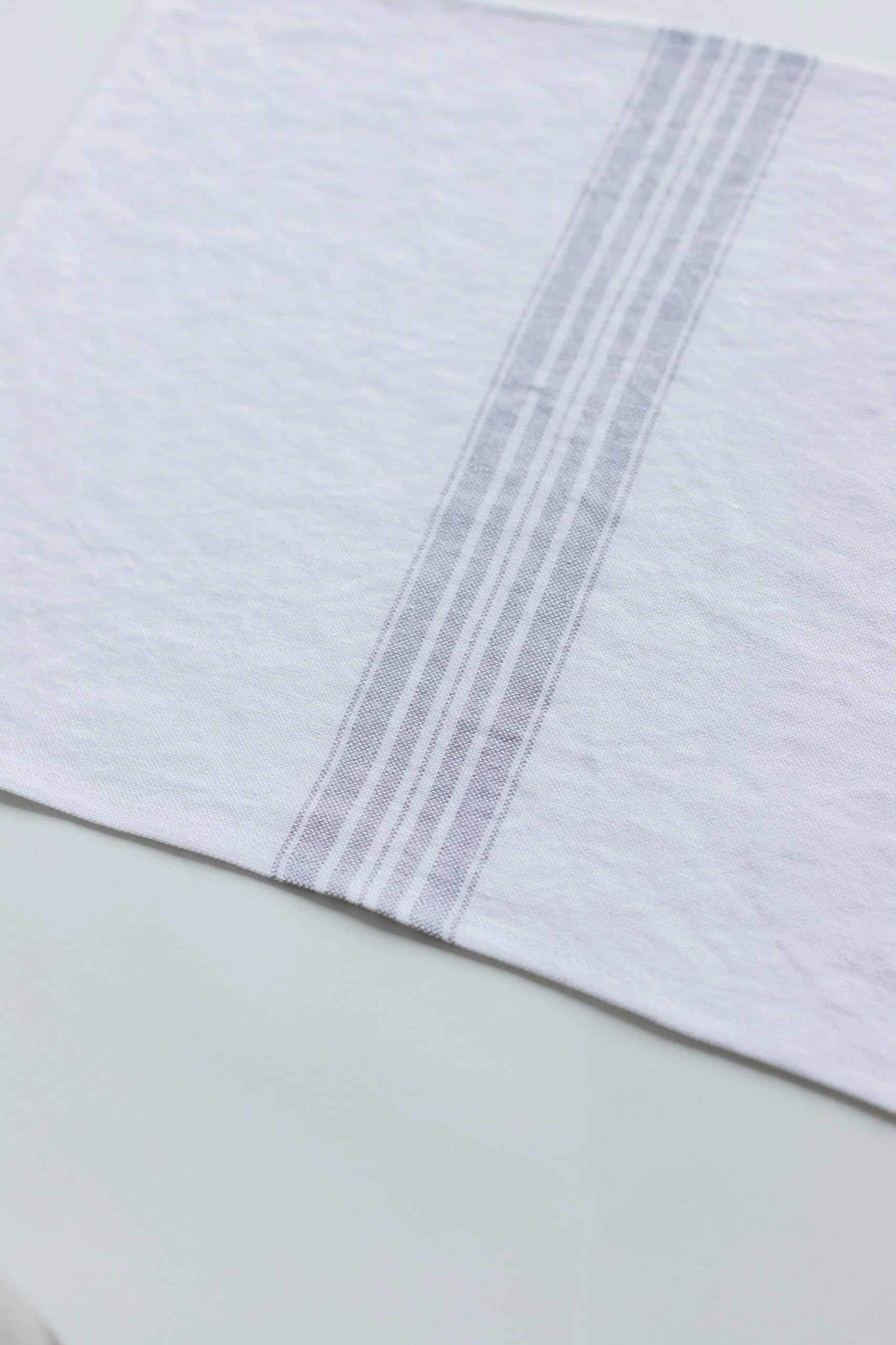 Close-up of a white placemat with gray stripes on a light green background