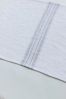 Close-up of a white placemat with gray stripes on a light green background