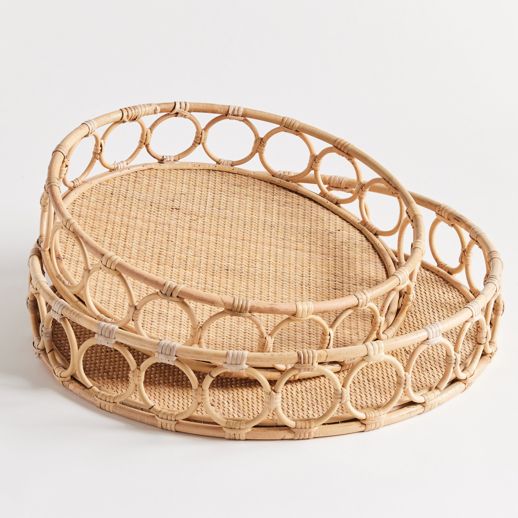 Two circular woven trays with circles around edge on white background